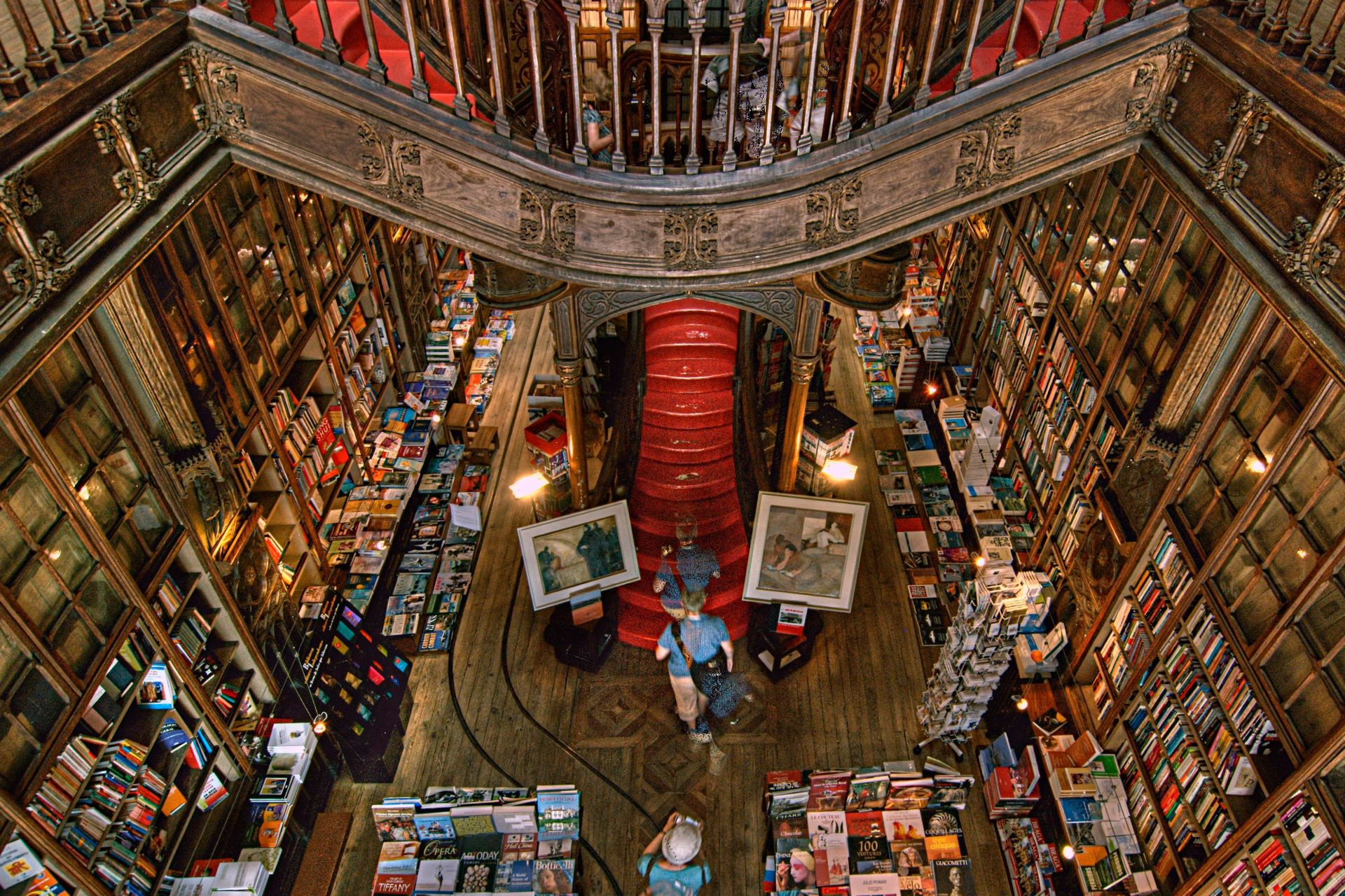 An intricately designed bookshop from above with red floors and wooden shelving climbing the walls