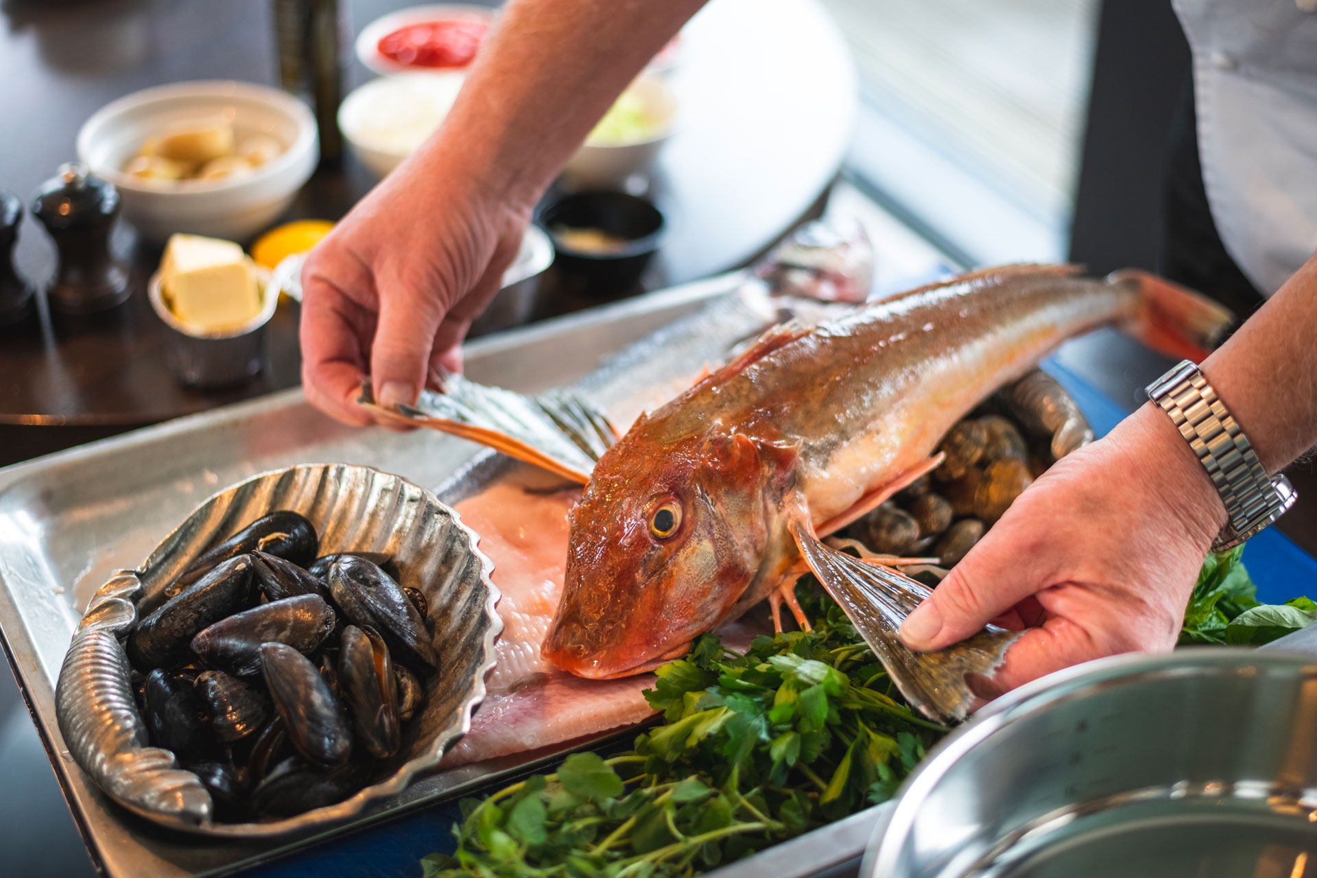 Hands preparing a fish for dinner service