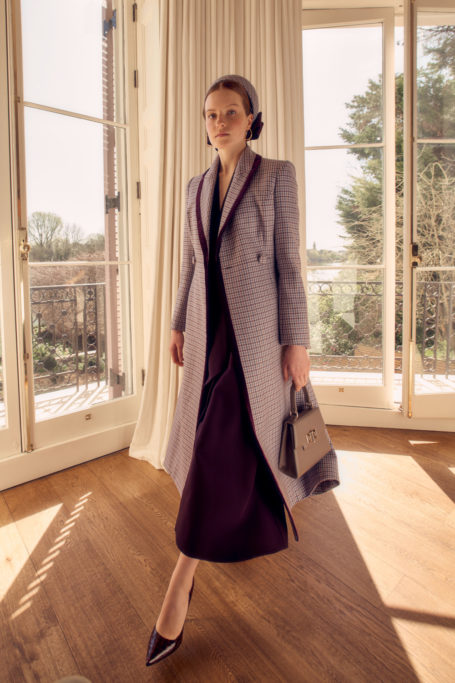Woman wearing coat and holding handbag from Suzannah London