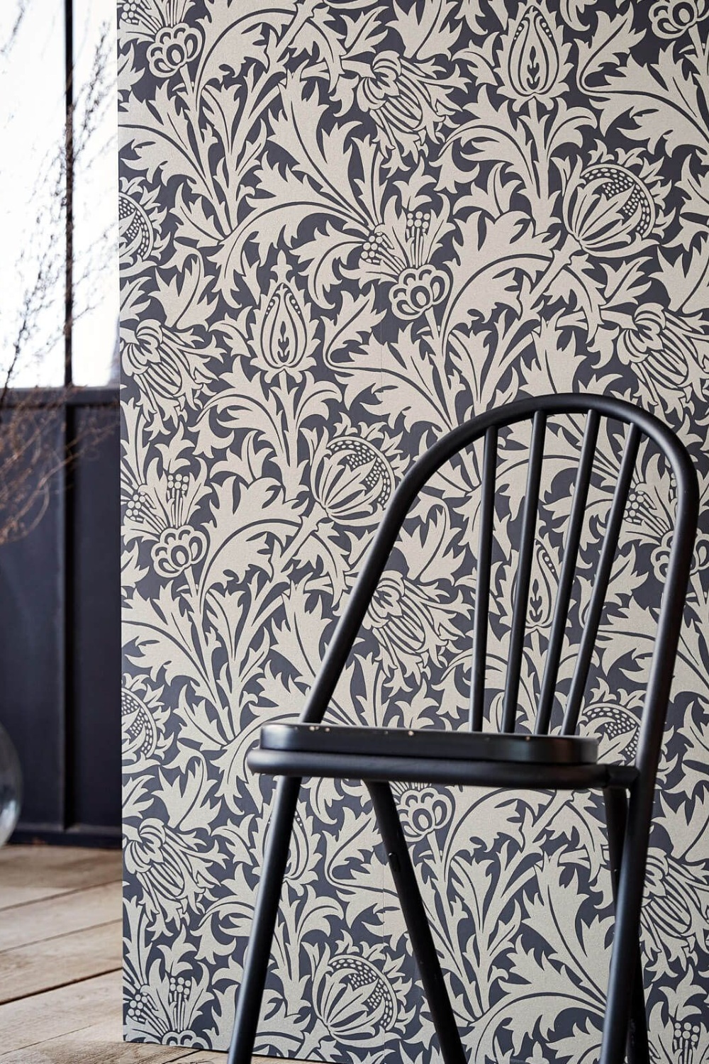 Close up of chair in front of black thistle wallpaper
