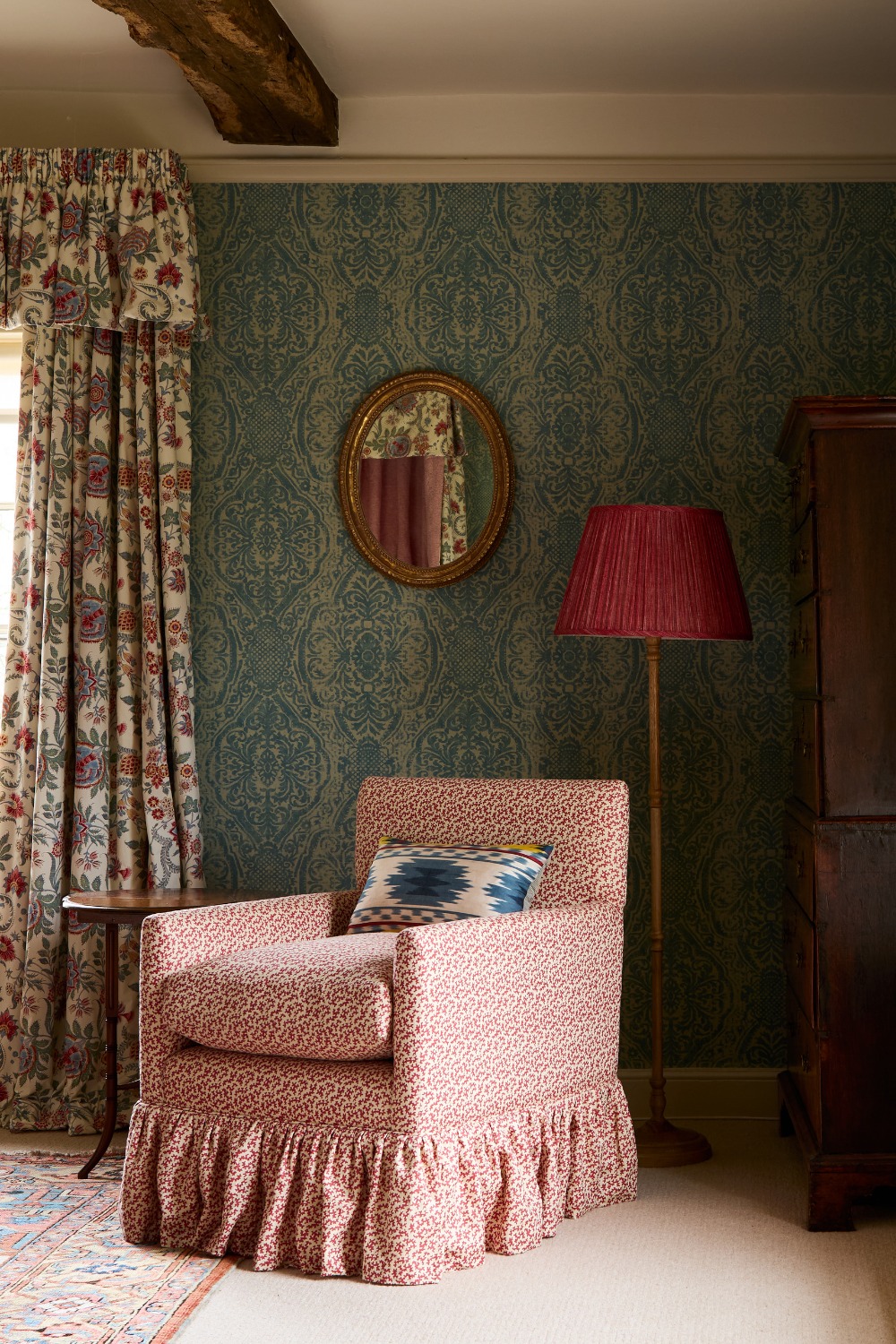 Red armchair in front of blur wallpaper and floral curtains