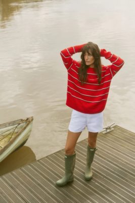 Woman wearing red jumper and white shorts from B Corp fashion brand With Nothing Underneath
