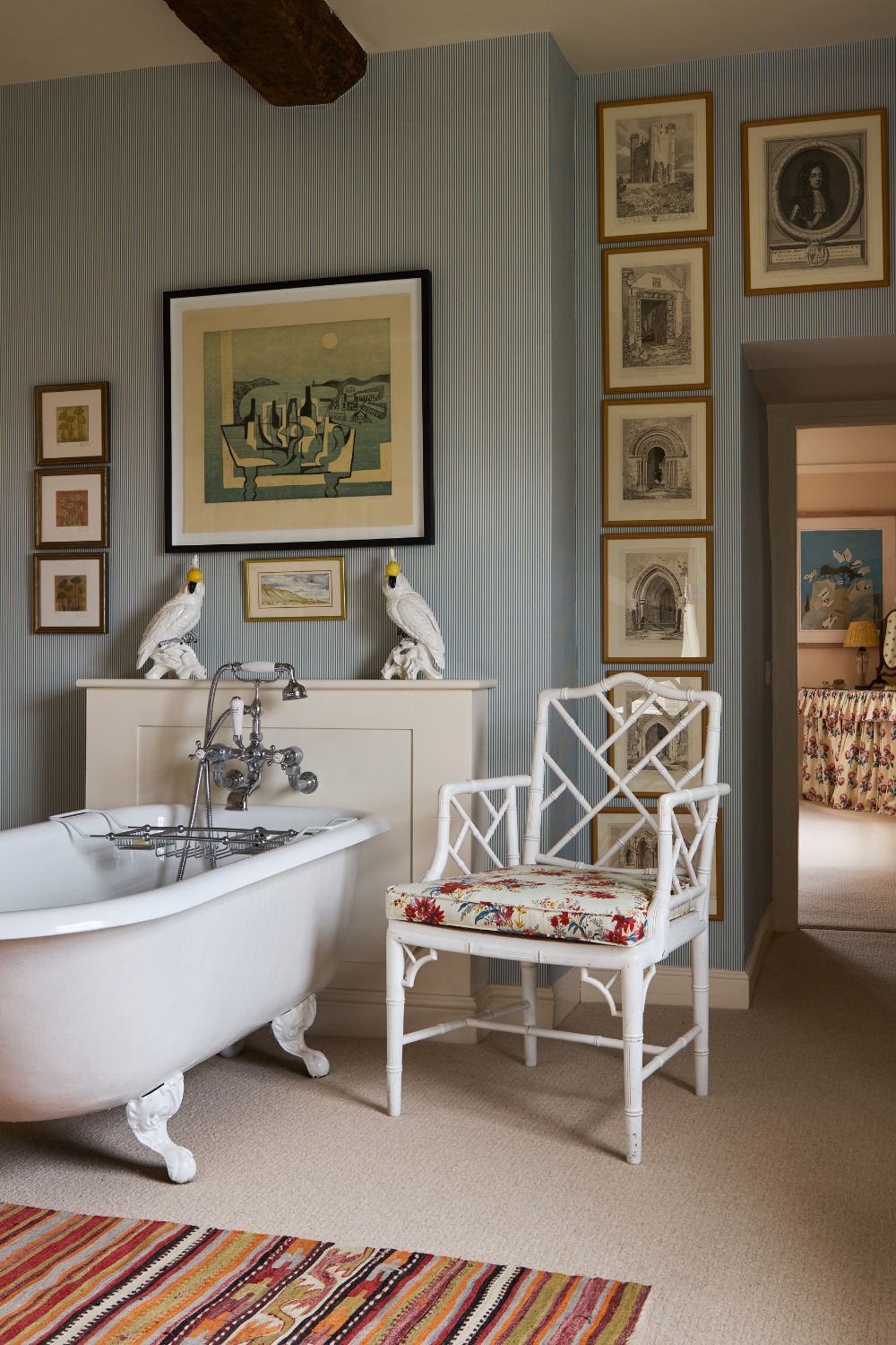 Blue bathroom with white tub and wooden chair, with art on the walls