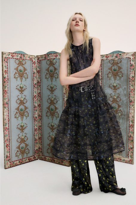 Woman in black dress stood in front of blue room divider