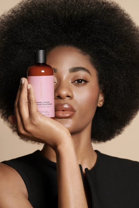 Woman holding up Monpure shampoo bottle