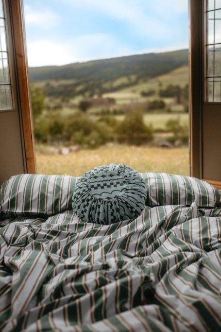 Bedding set against open doorway with view onto field