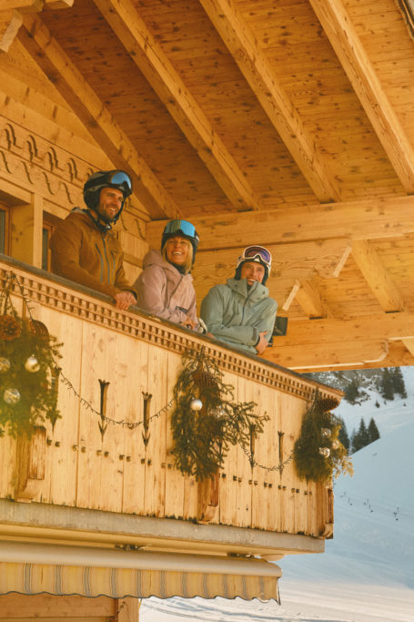 Three skiers on a chalet balcony