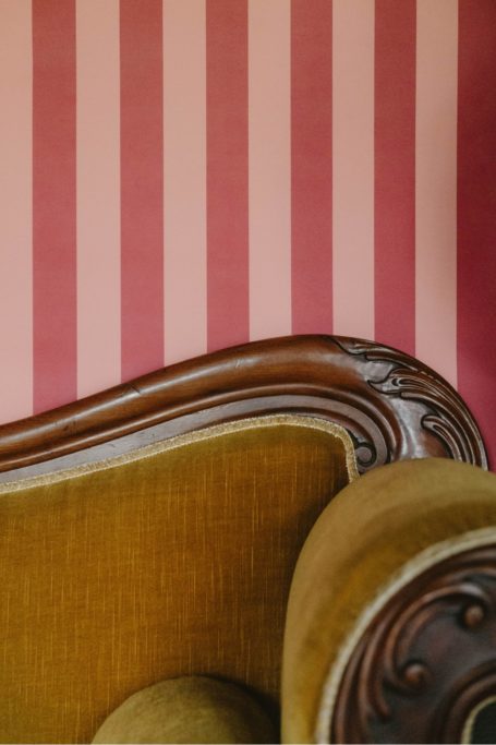 Pink striped wall and mustard sofa