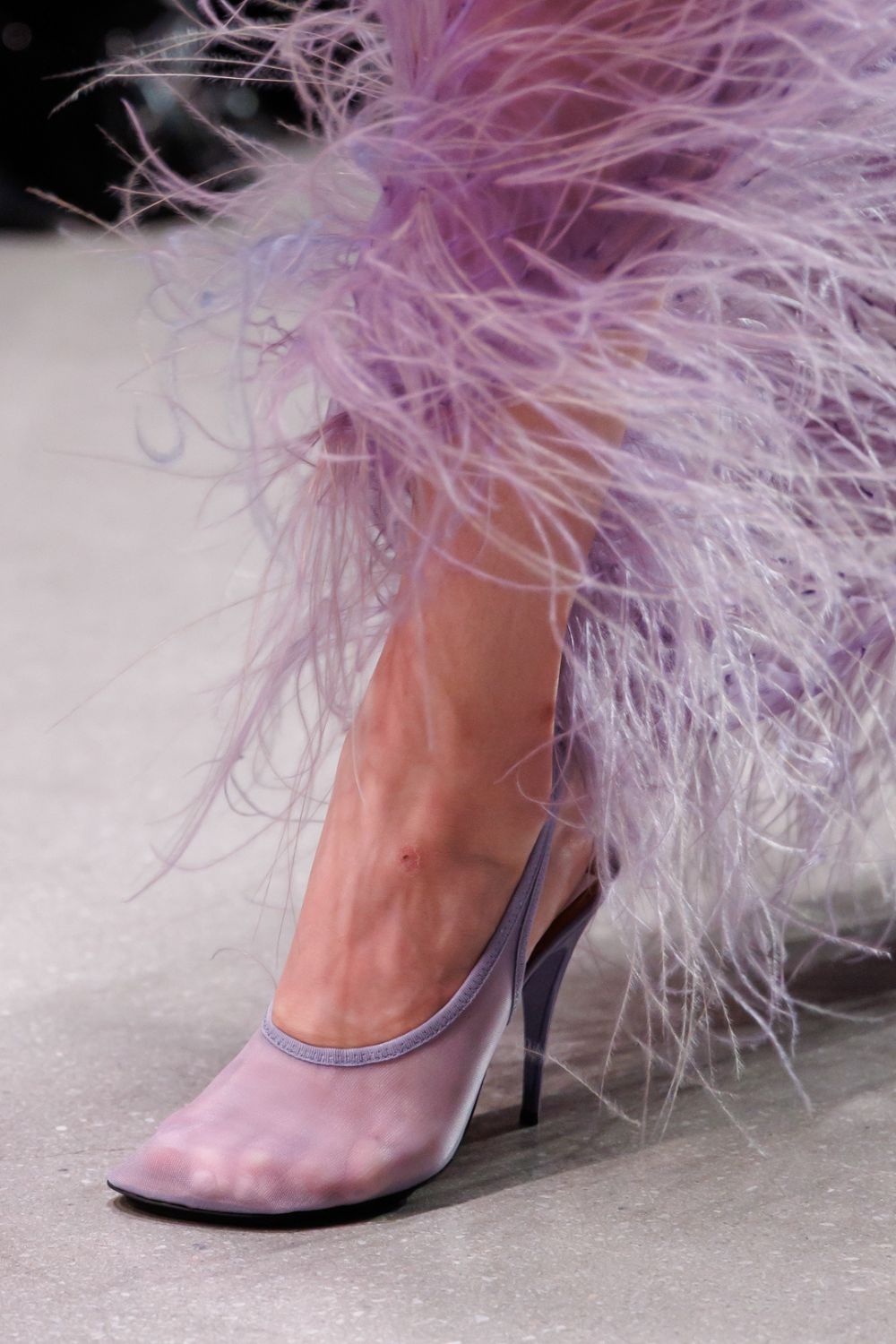 Close up of someone wearing purple heel and feathers