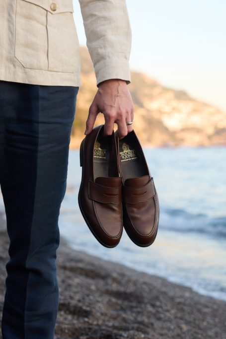 Man holding brown loafers from Crockett & Jones SS26