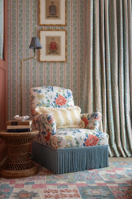 Blue, cream and pink floral chair with floral wallpaper behind it