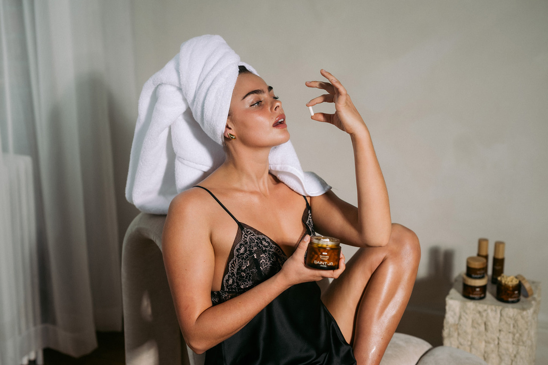 A woman with a towel on her head taking a supplement