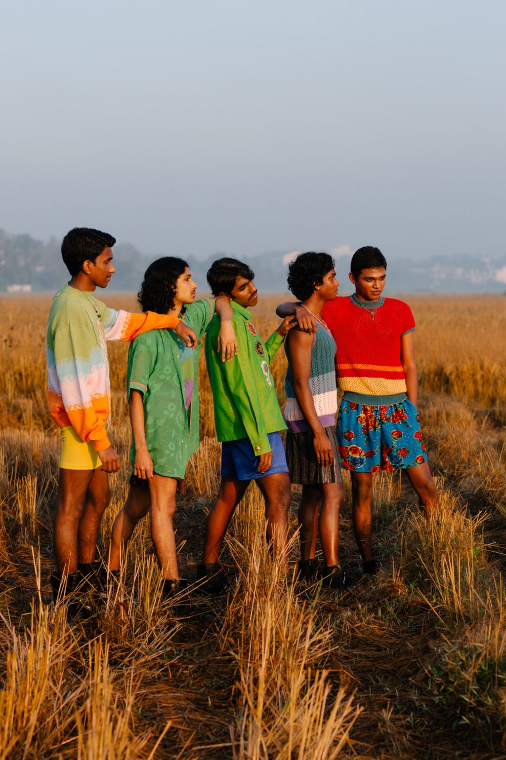 A photo of five young south Asian men in a hay field