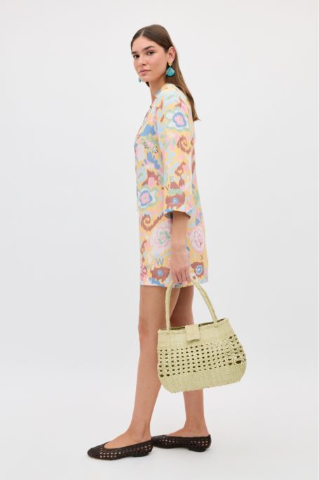 Woman wearing 70s printed mini dress and holding woven bag