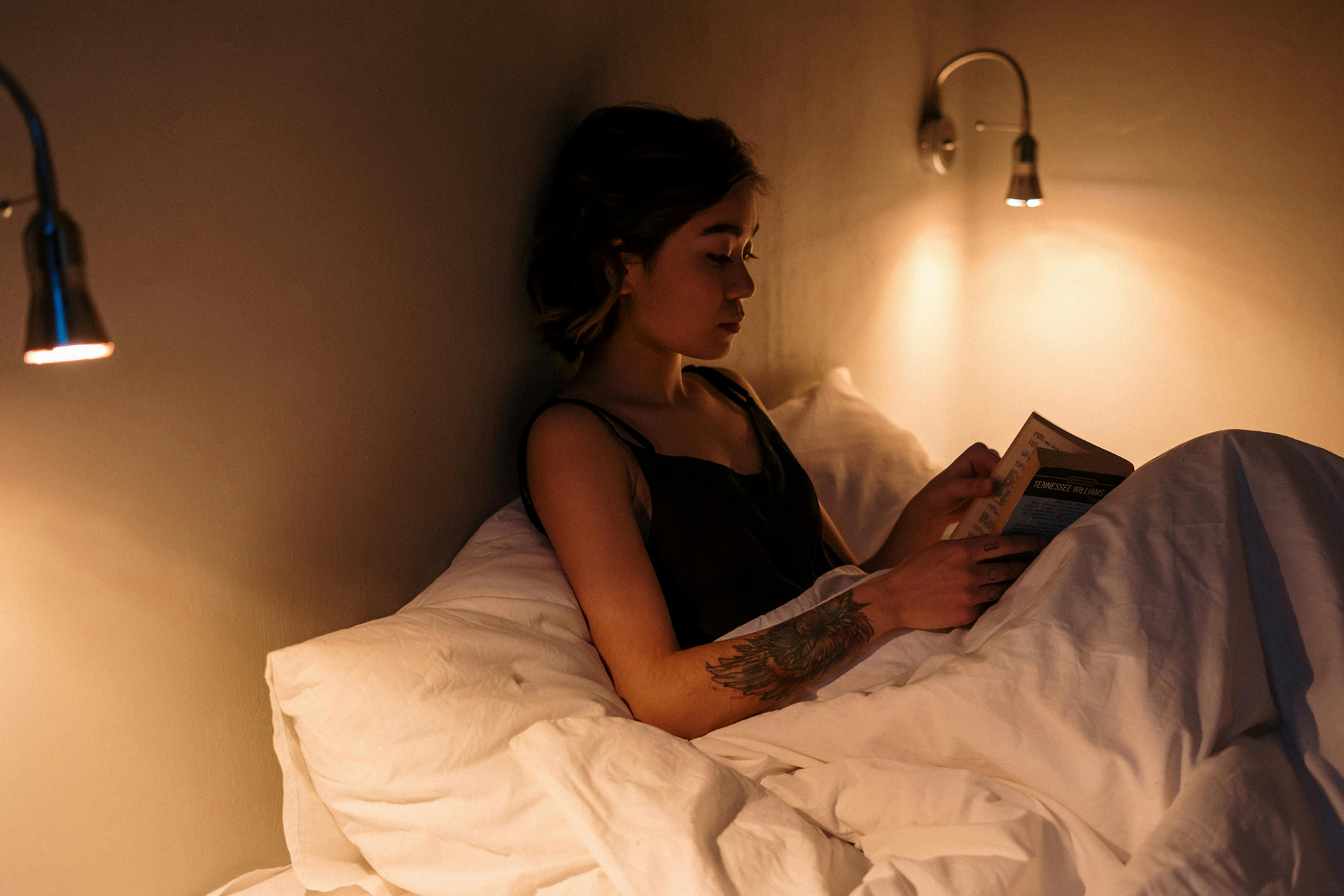Woman reading in a low-lit room in bed