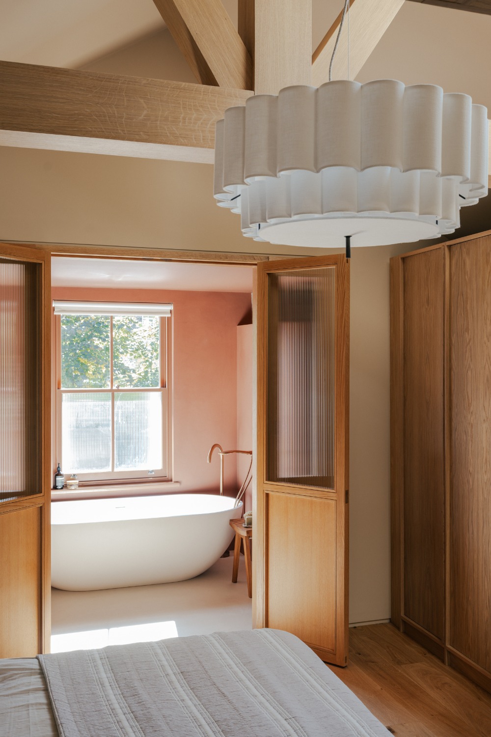 Light-filled room connecting to bathroom with freestanding bath