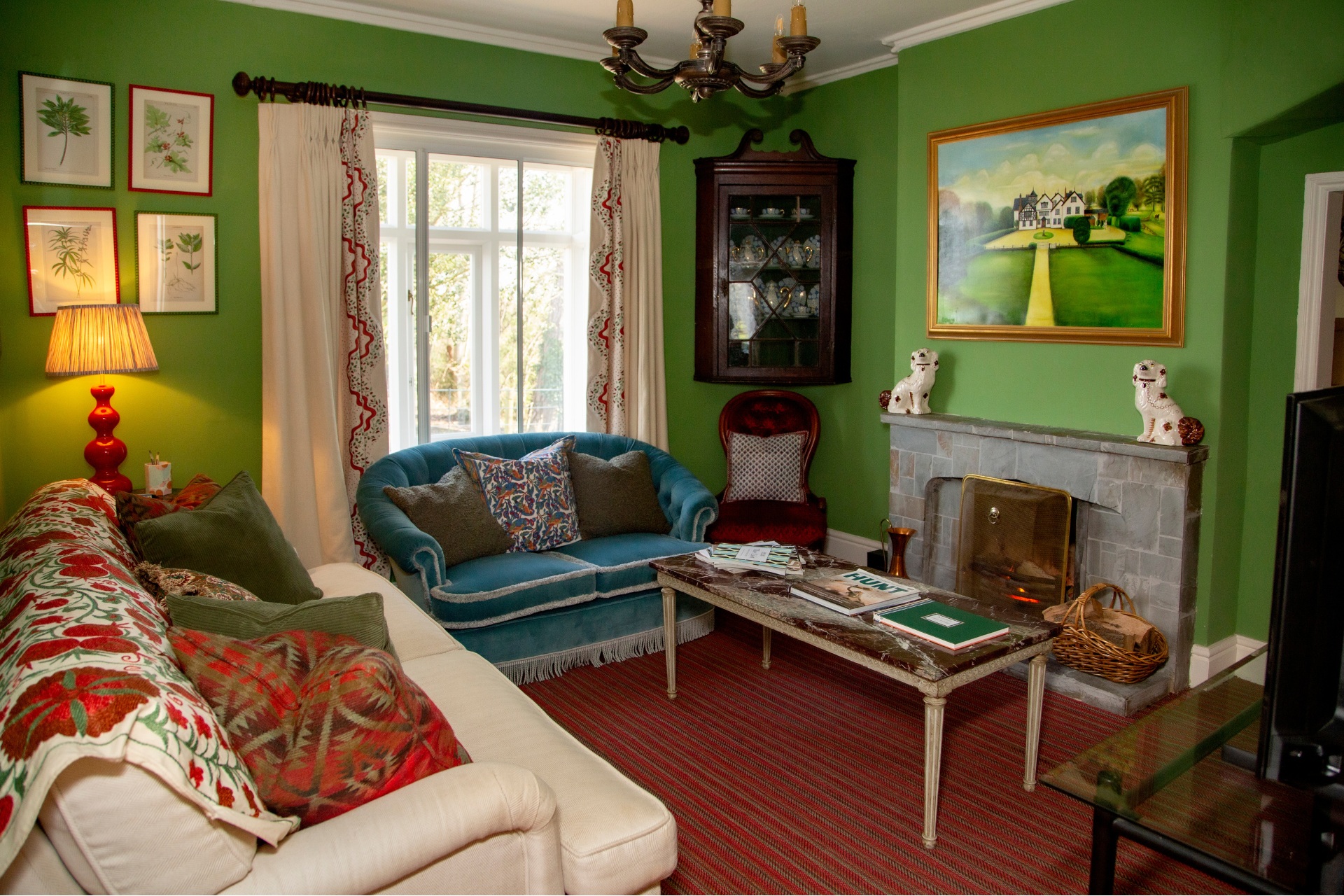 Green sitting room with stone fireplace and antique furniture