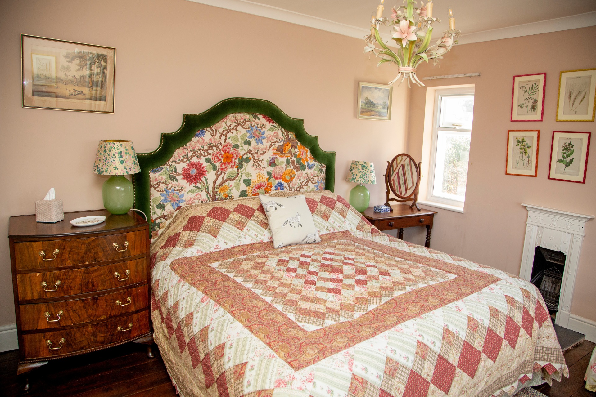 Pink bedroom with floral headboard and prints on the wall in colourful frames