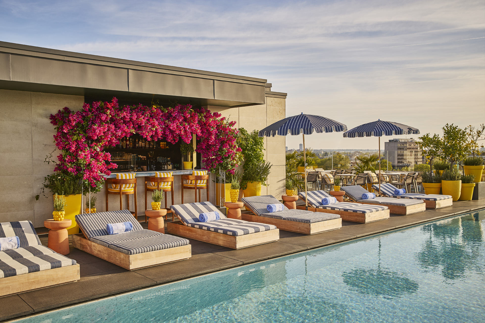 Striped sun loungers beside a rooftop pool.