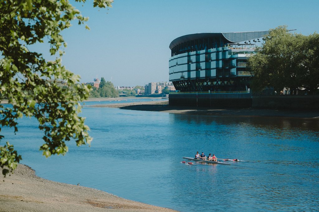 Fulham Pier Hotel viewed from across the water with rowers paddling in between