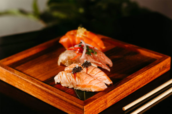 Three nigiri on a wooden plate