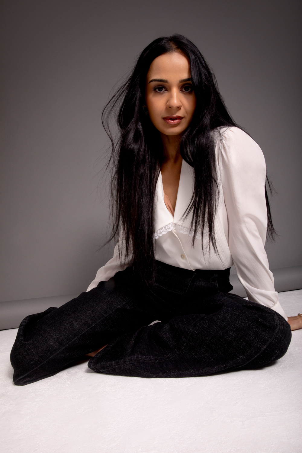 Ambreen Razia sitting on the floor in a shirt and trousers