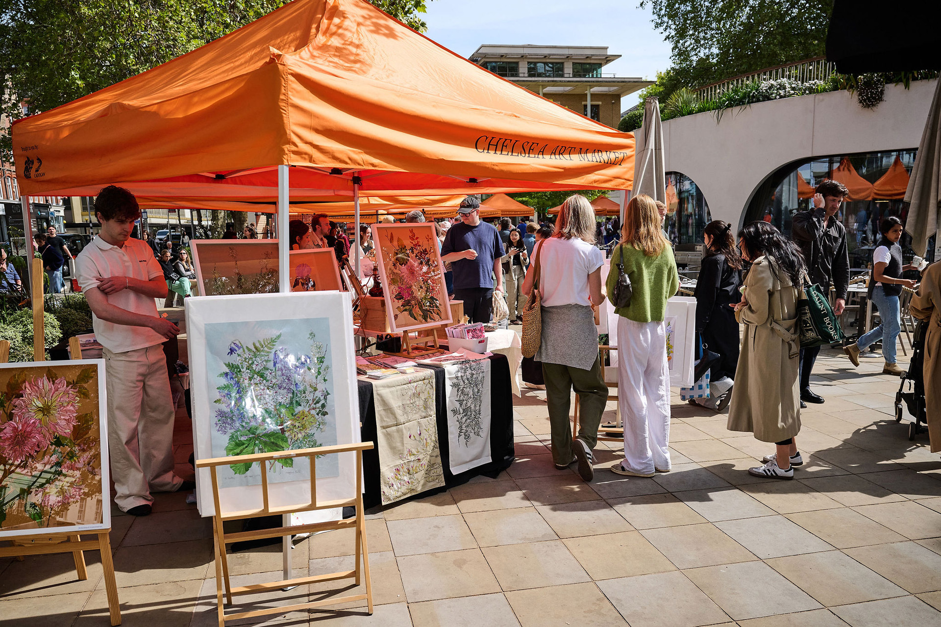 A stall holder at Chelsea Art Market on a sunny day.