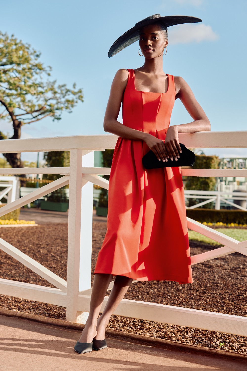 Woman in red dress and black hat from Phase Eight summer occasionwear edit