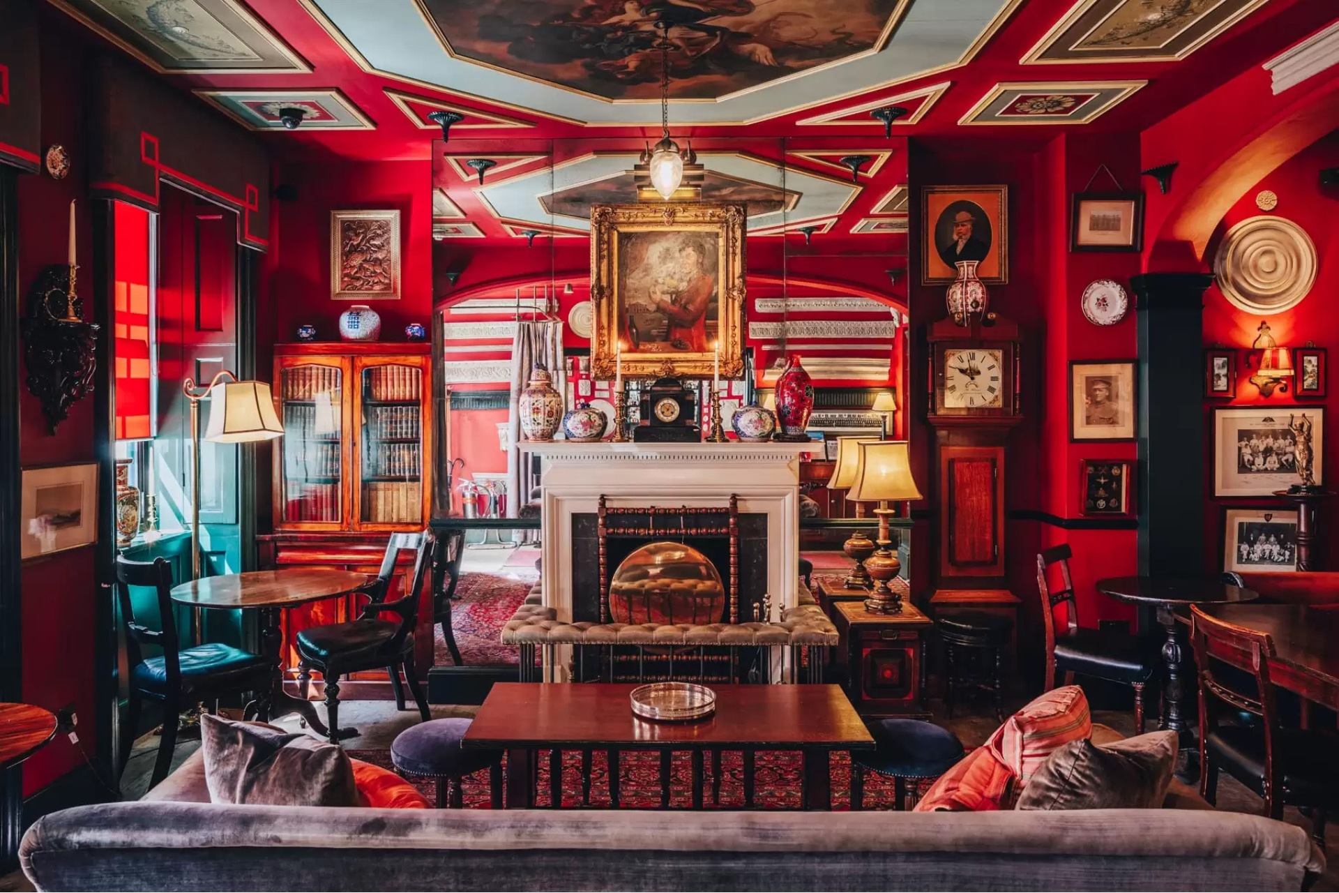 Zetter Marylebone interiors - red walls with wooden panels and tables, patterned upholstery and art prints on the walls