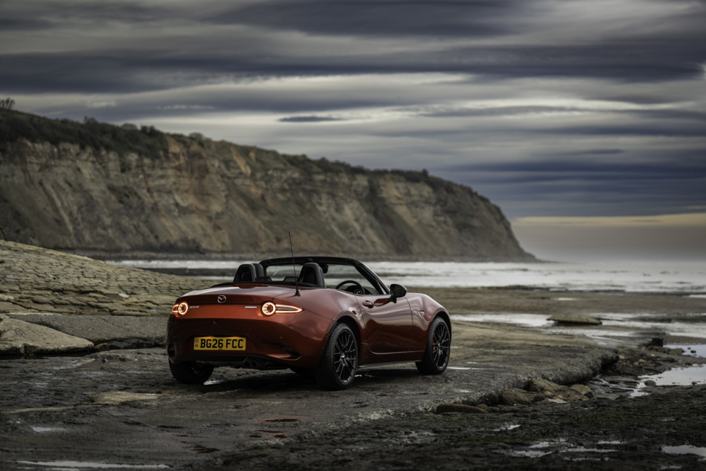 The rear of a red MX-5 Roadster beside the sea