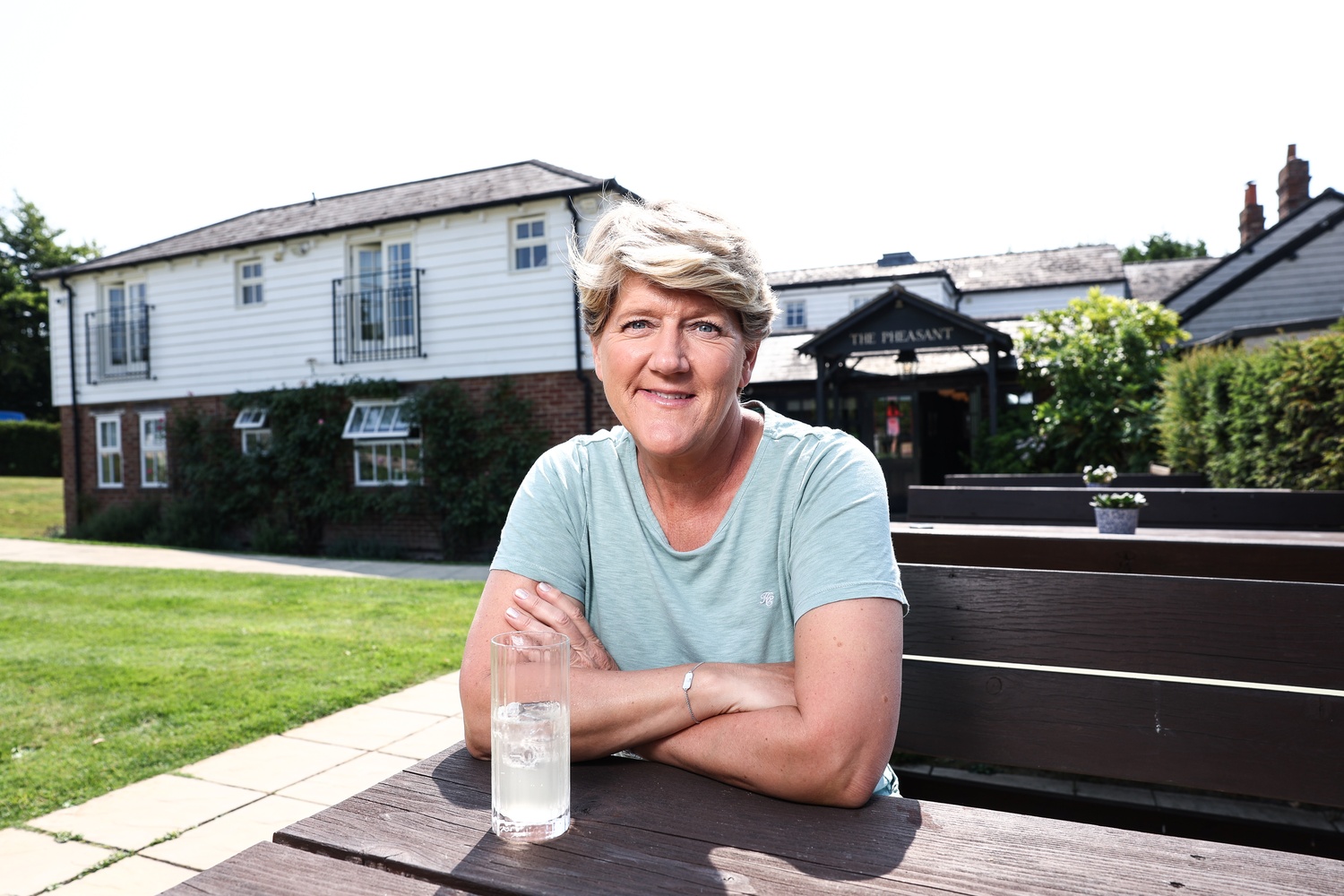 Clare Balding sitting outside a cottage with a drink