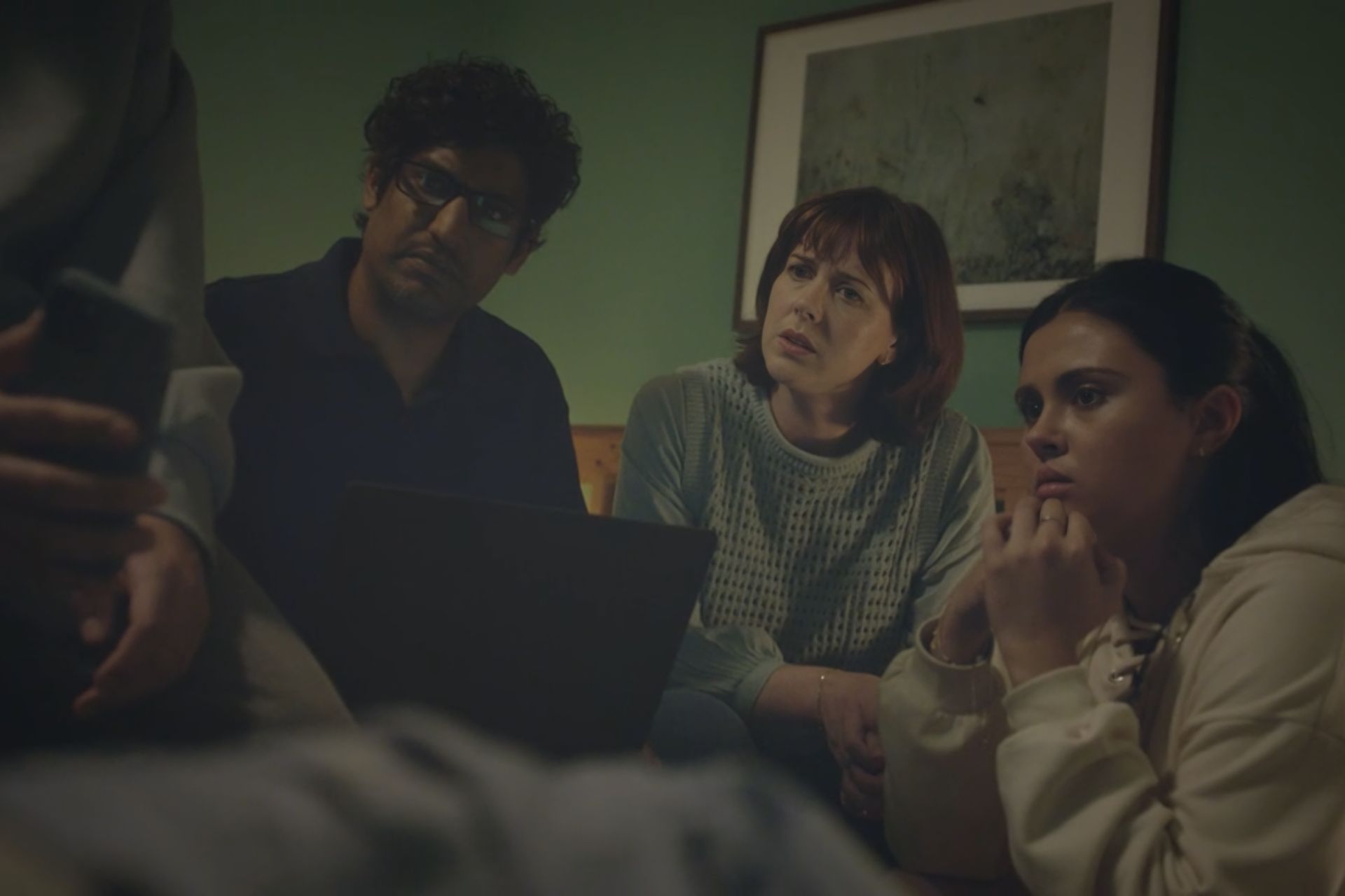 A still from Hunting Alice Bell featuring two parents and thier child looking concernedly at a screen