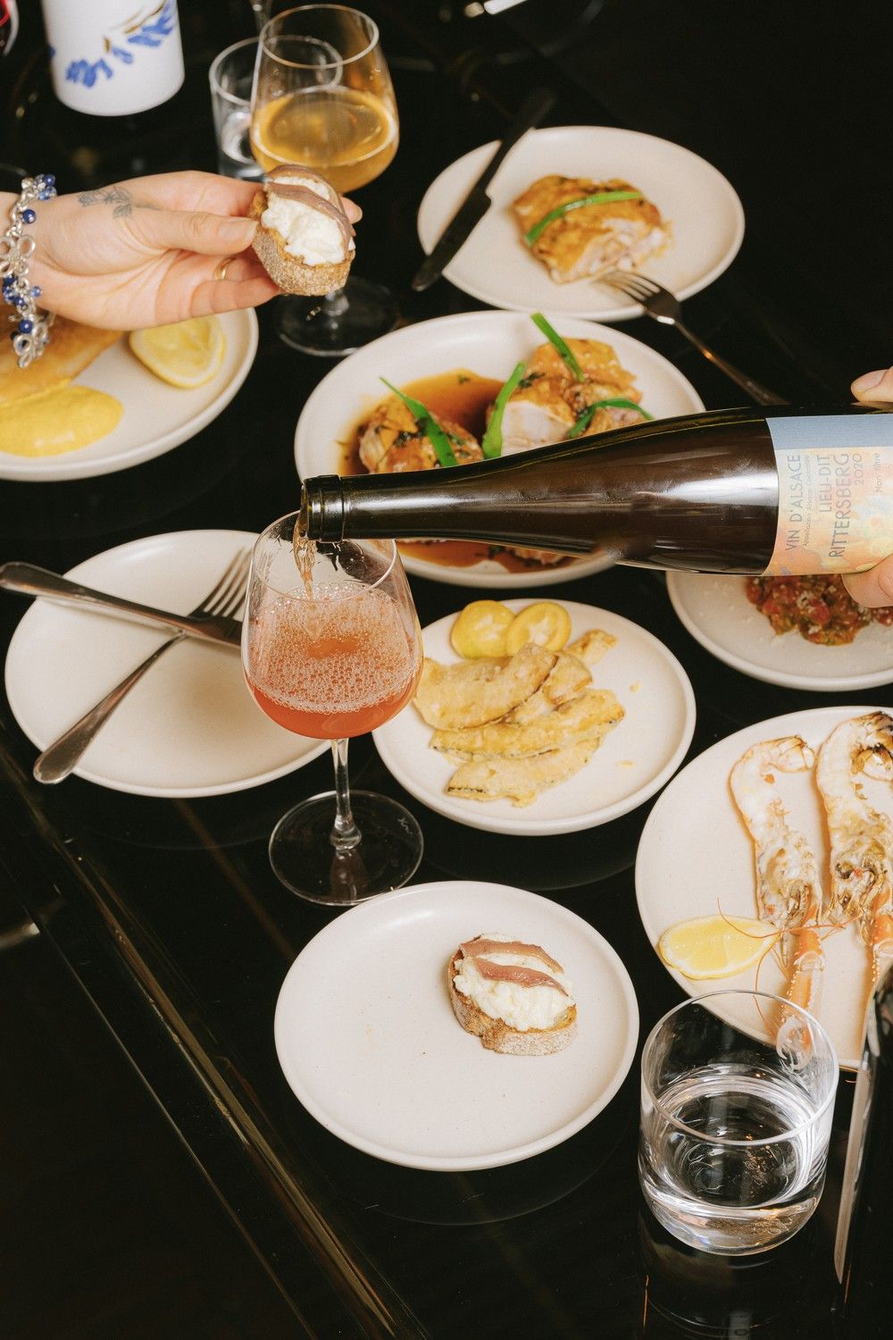 An array of dishes of food on a table, with a wine bottle being poured into a glass