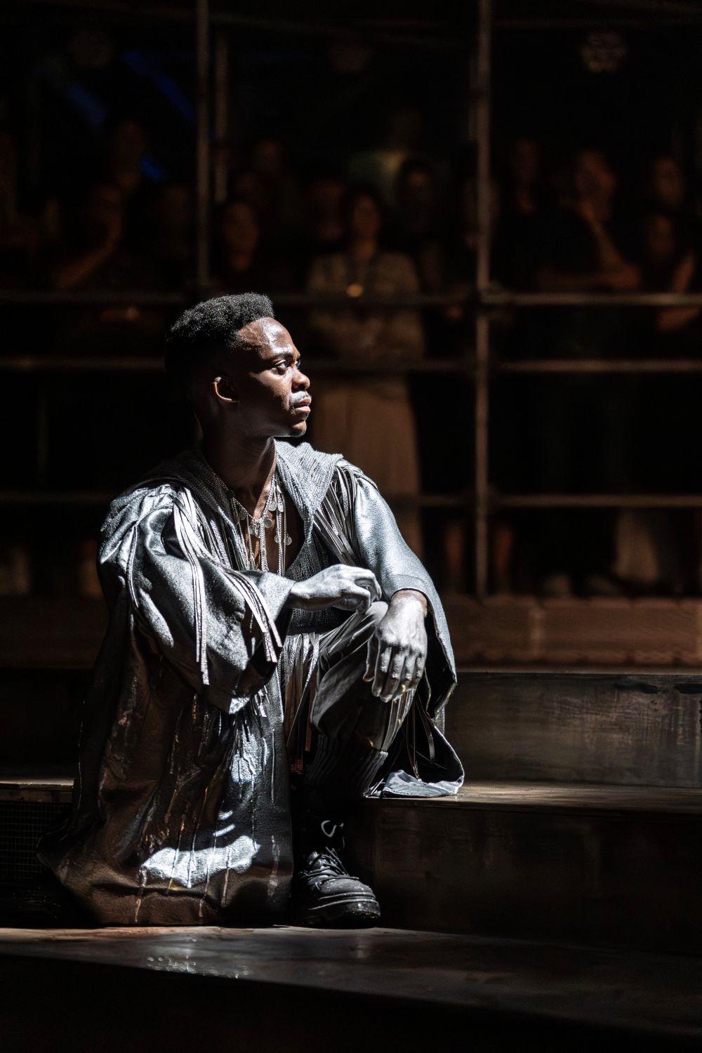 A shadowed image of Tyrone Huntley as Judas crouching on stage in Jesus Christ Superstar.