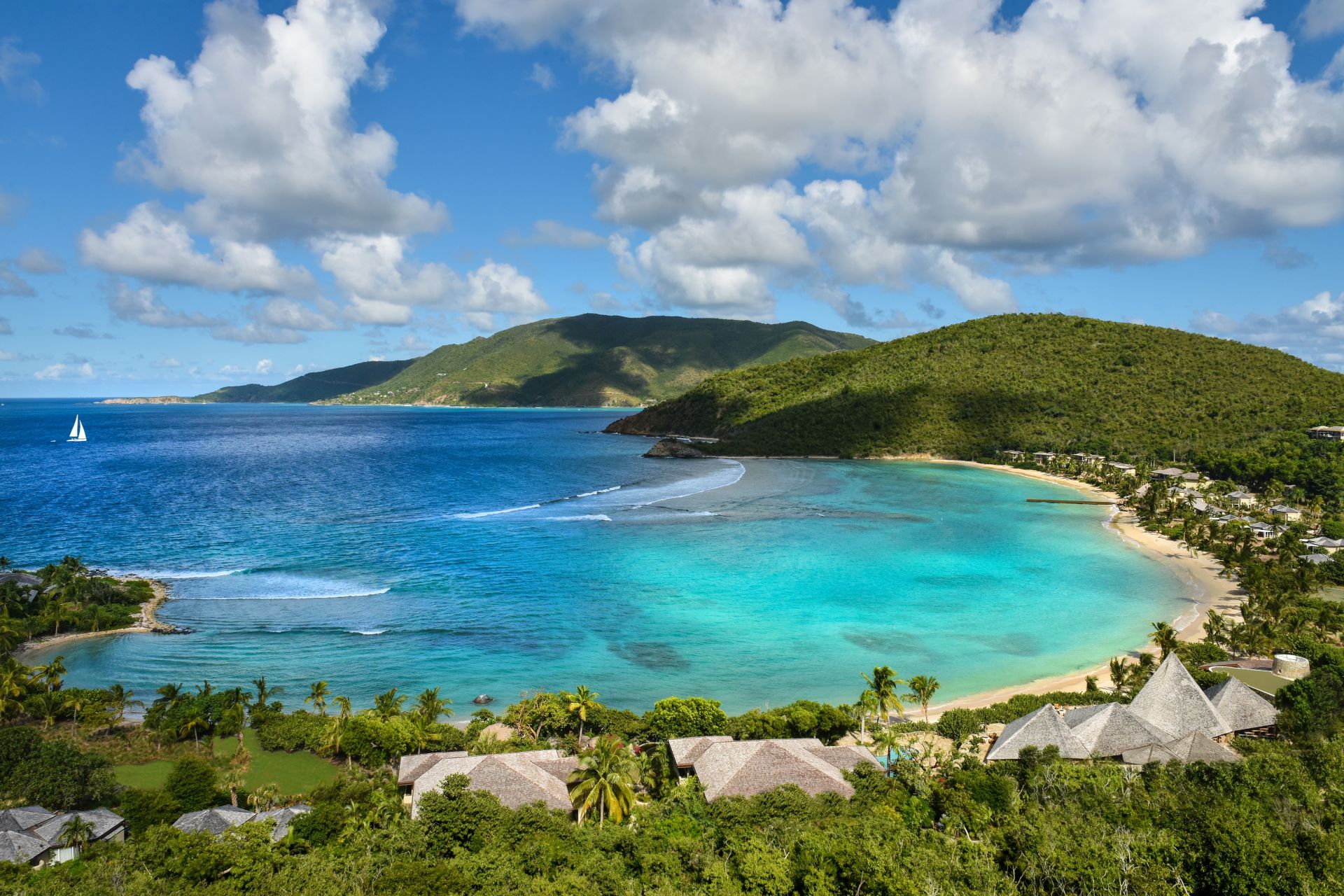 Aerial view of Rosewood Little Dix Bay with turquoise waters in a curving tree-covered bay