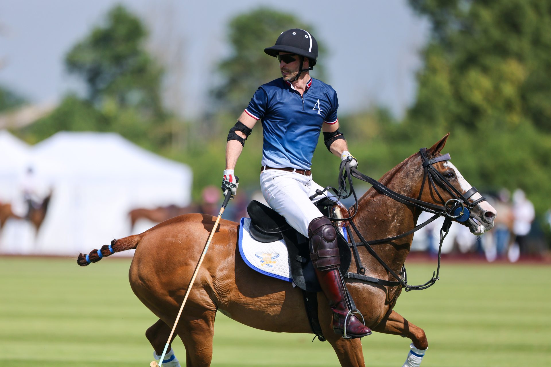 A side shot of Prince William in a polo uniform riding a polo pony.