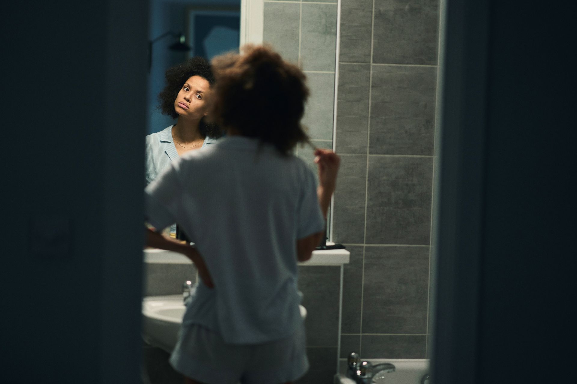 A shot of Gugu looking into a mirror, taken from behind