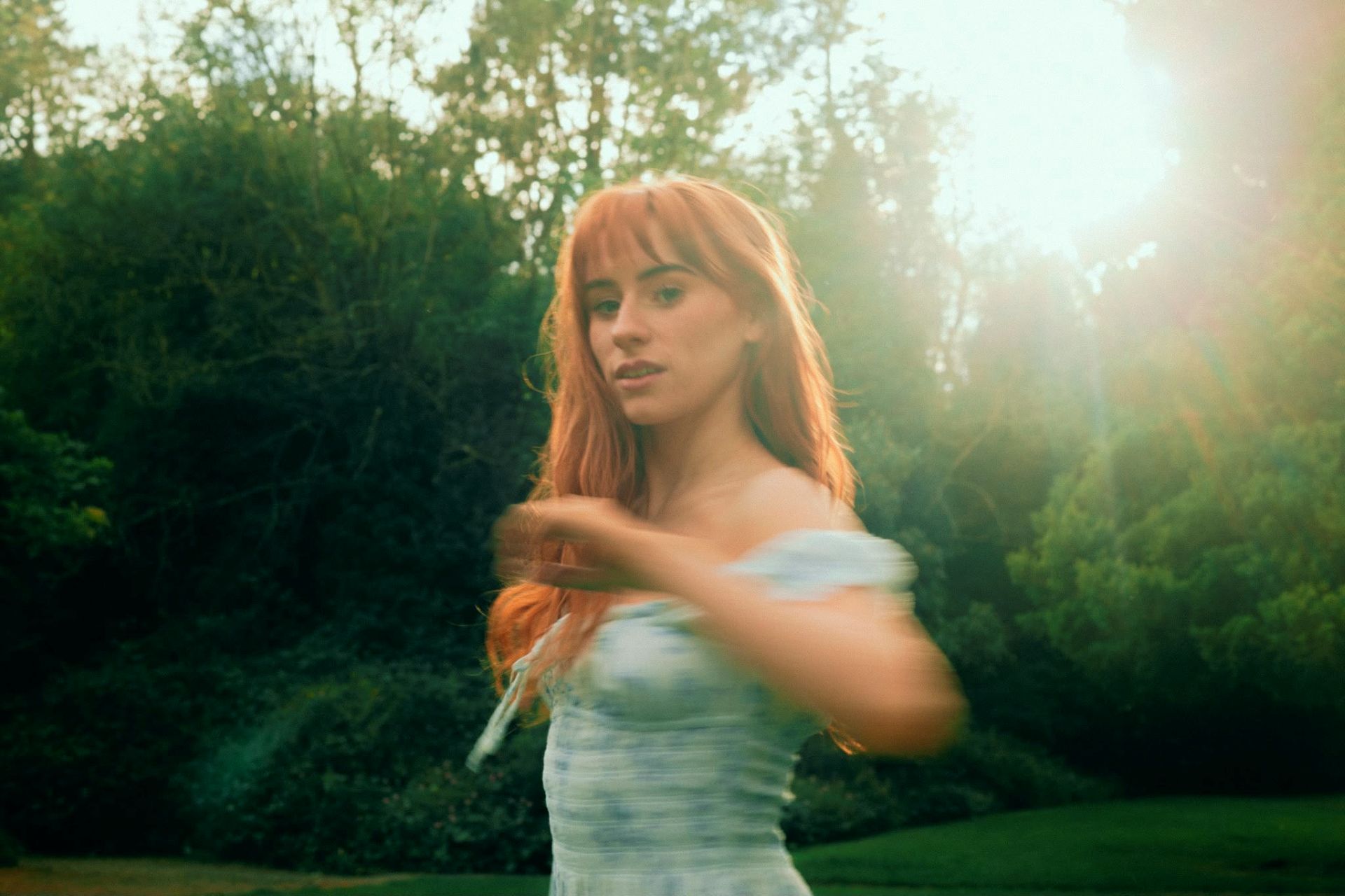 Aisling Sharkey in motion, wearing a dress surrounded by trees