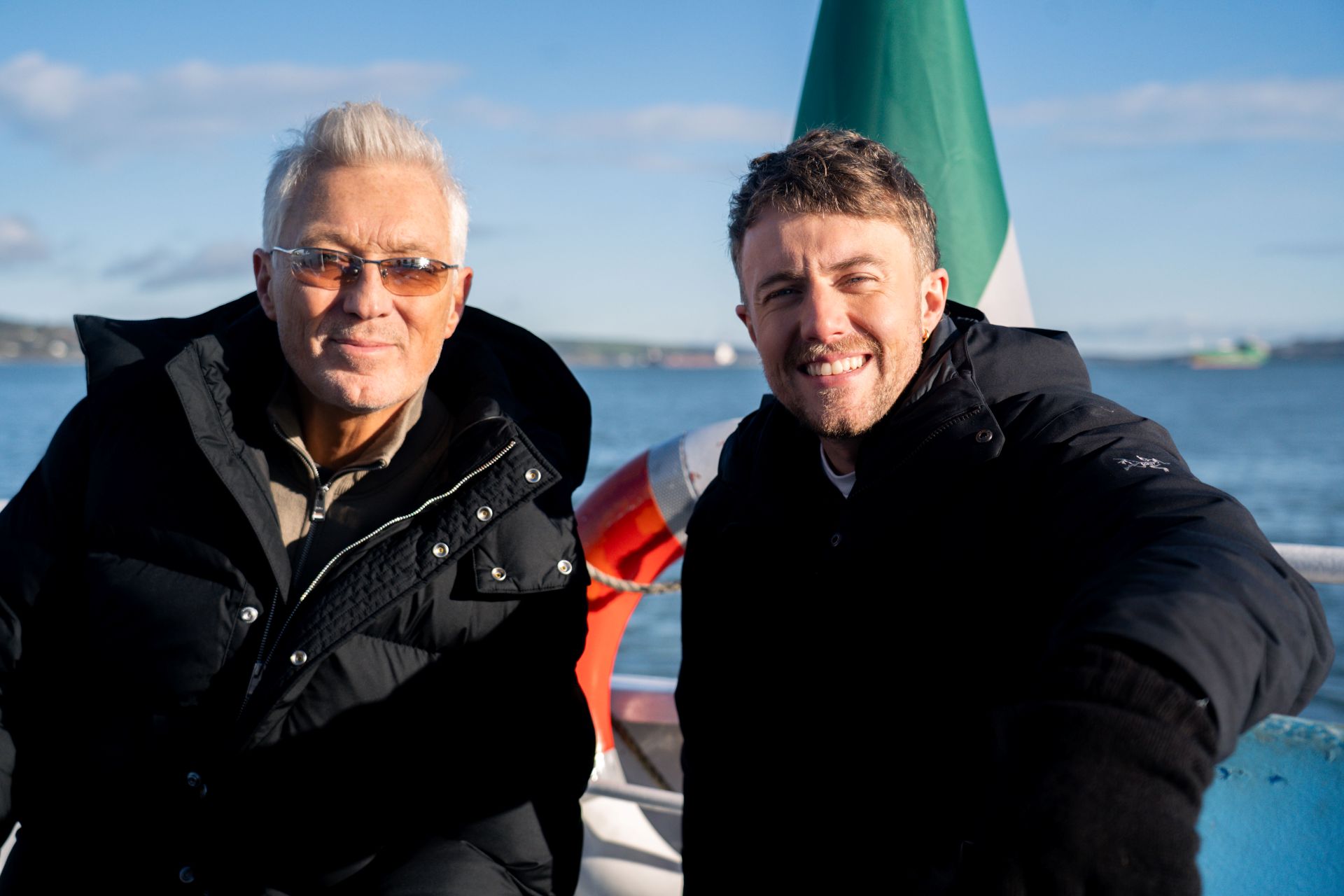 Martin and Roman Kemp side by side, smiling, on a boat