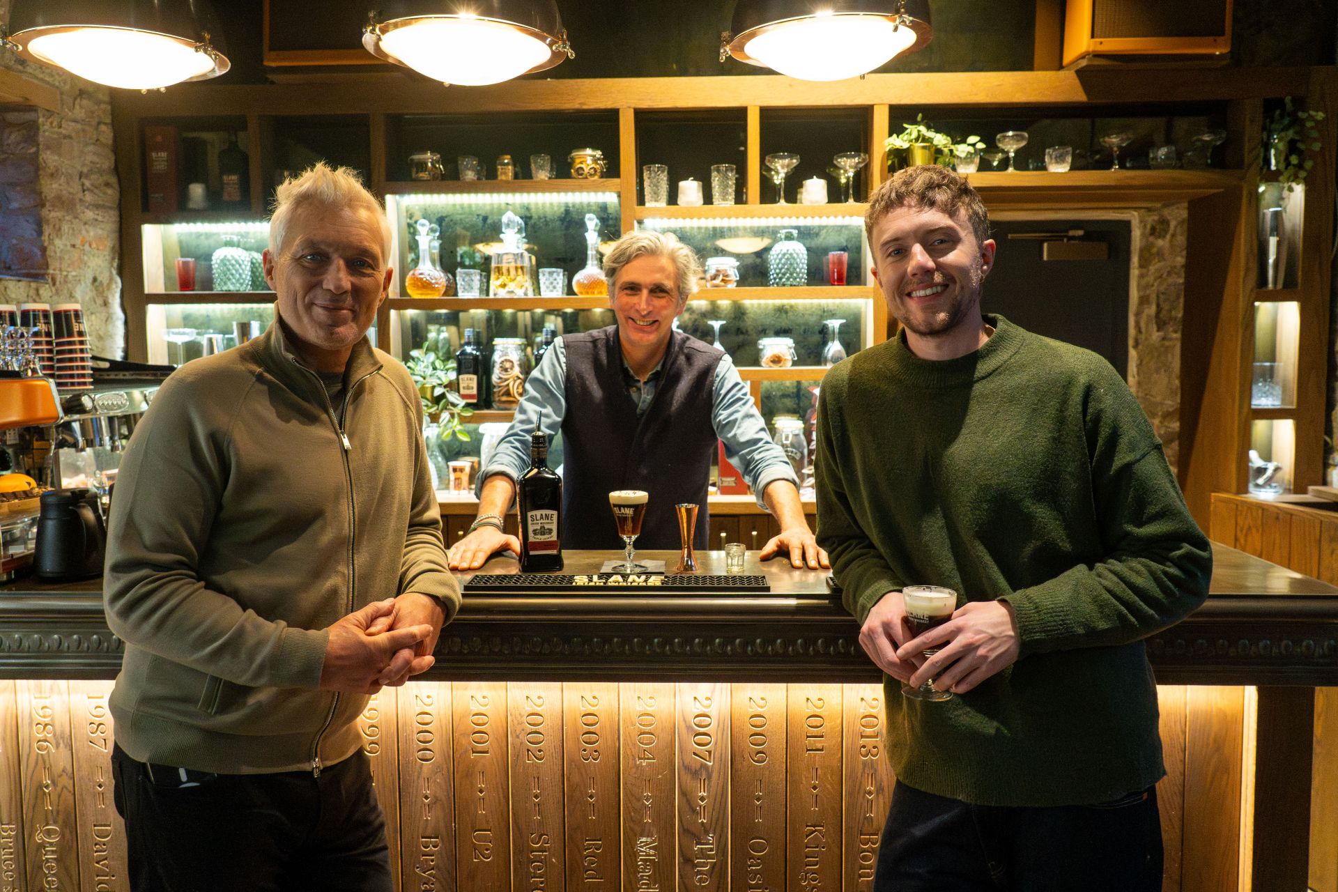 Martin and Roman smiling with a man behind the bar