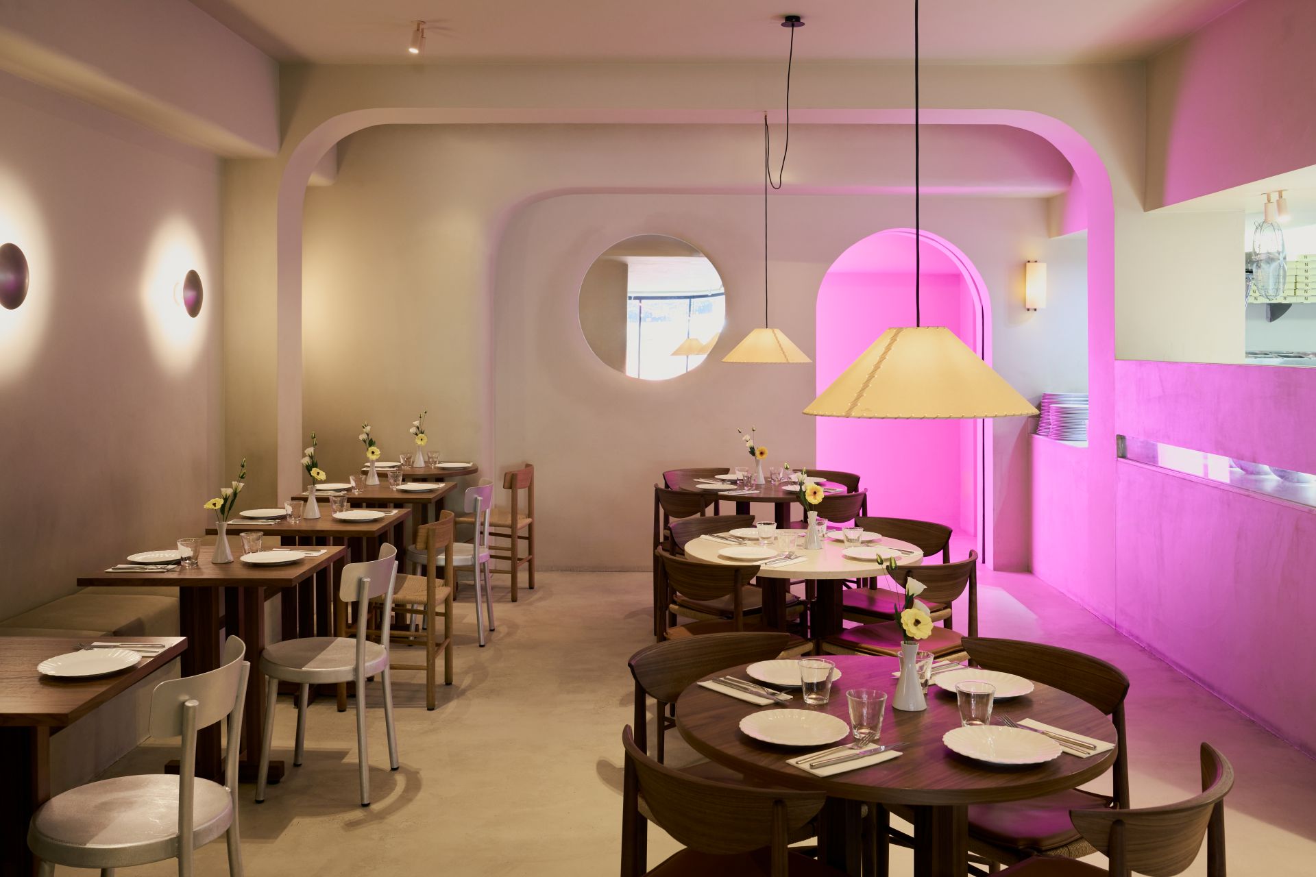 The modern-looking dining room with light wood tables and curved concrete walls