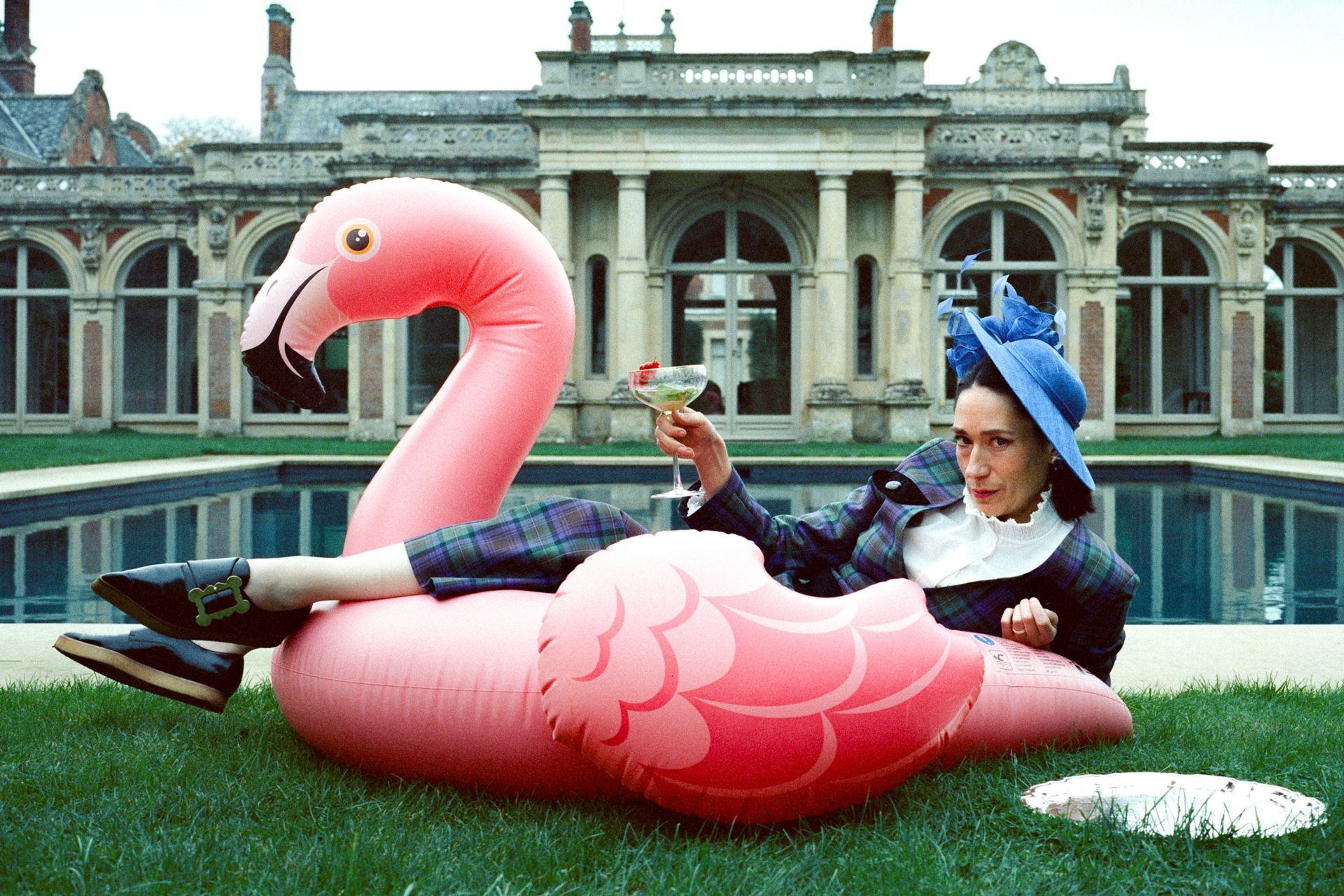 Sian Clifford outside Somerleyton Hall lounging on an inflatable flamingo