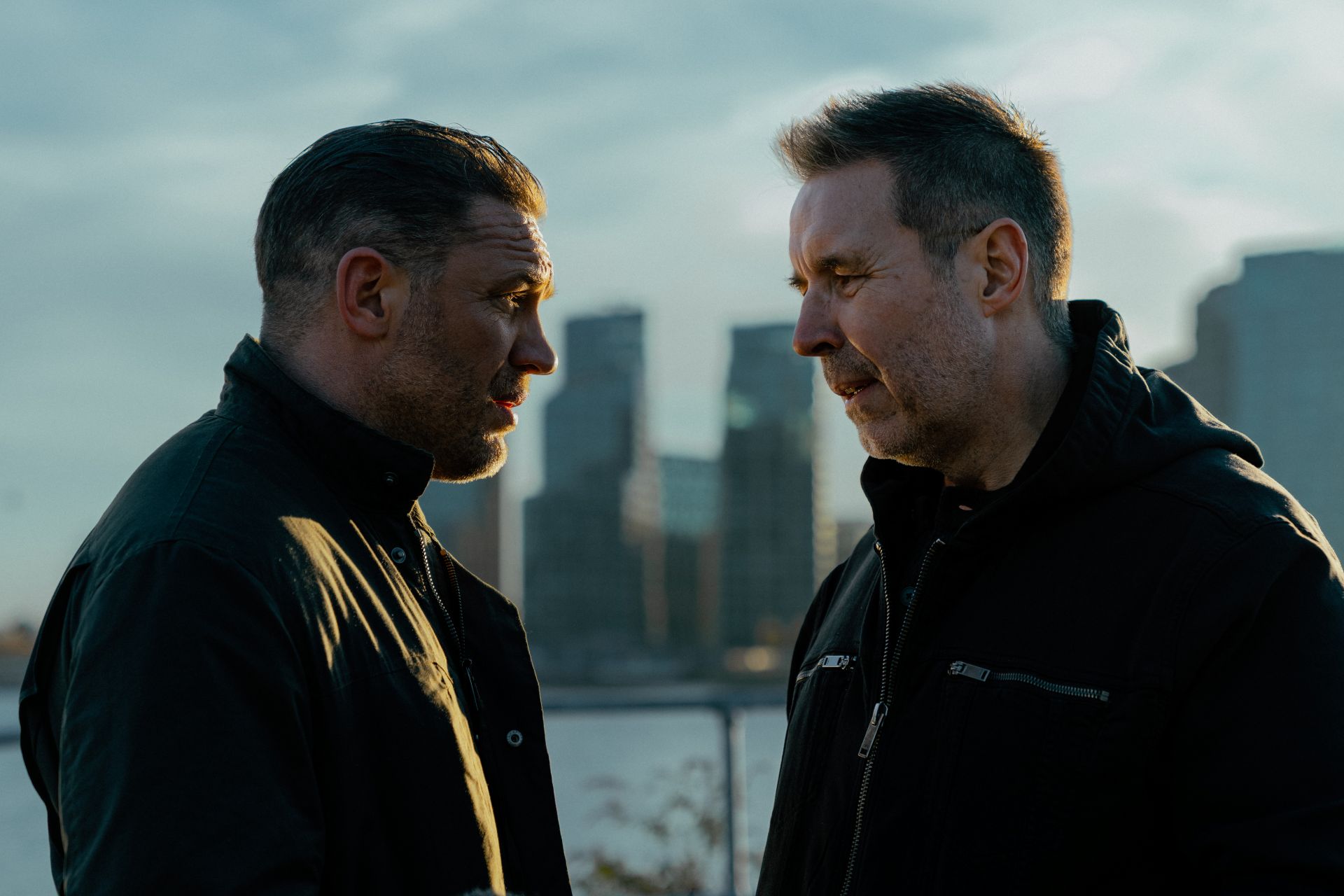 A still from MobLand featuring Tom Hardy and Paddy Considine having a serious conversation against a city backdrop
