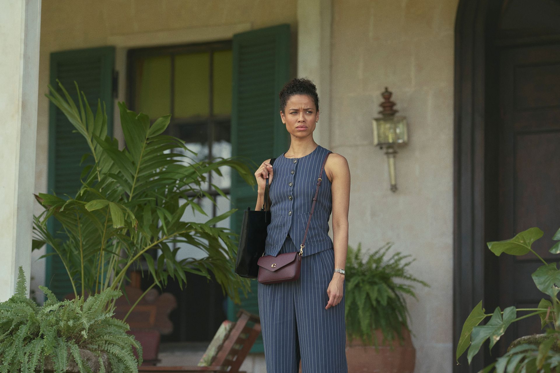 Gugu in a suit standing outside a leafy house in Jamaica